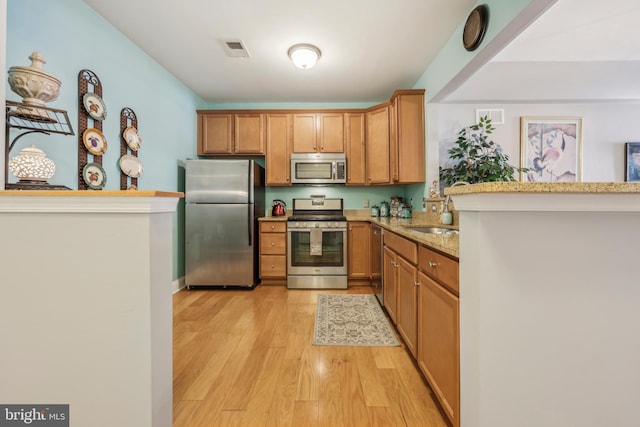 9200 Charleston Dr Unit 408, Manassas, VA 20110 - kitchen featuring stainless steel appliances, light wood finished floors, light stone counters, a sink, and a peninsula