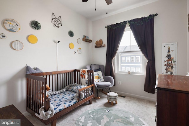 bedroom featuring baseboards, carpet flooring, a crib, and ceiling fan