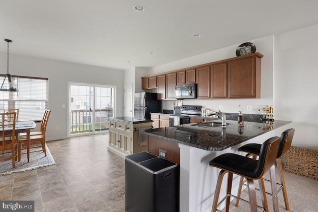 kitchen featuring a sink, electric stove, freestanding refrigerator, a peninsula, and stainless steel microwave