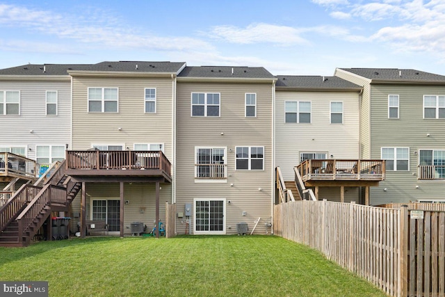 rear view of property with a fenced backyard, a deck, a lawn, and stairway