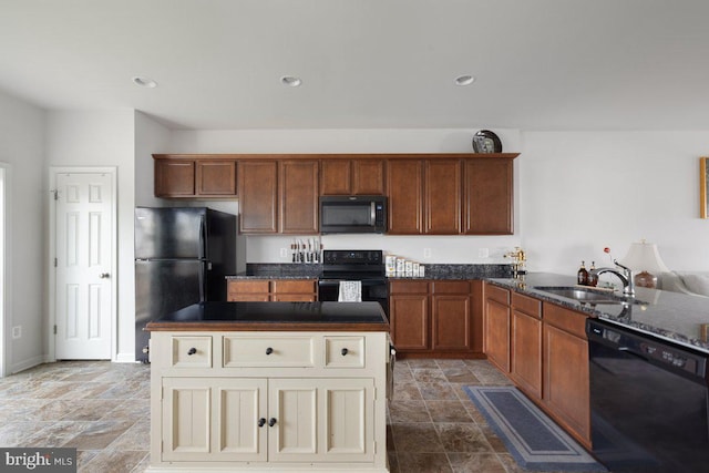 kitchen featuring a sink, dark stone countertops, stone finish flooring, a kitchen island, and black appliances