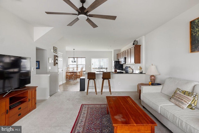 living room featuring baseboards, ceiling fan, and light carpet