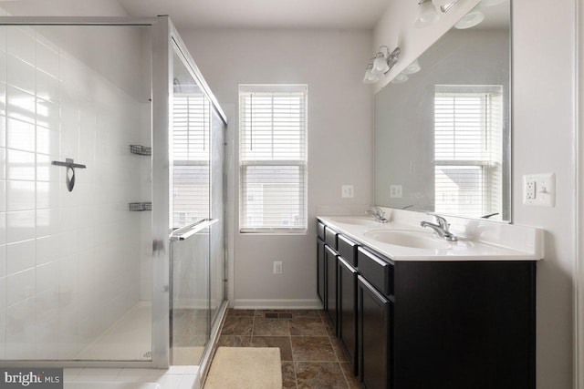 bathroom with baseboards, a wealth of natural light, a sink, and a stall shower