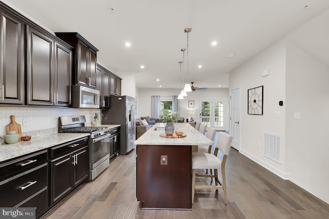 kitchen with appliances with stainless steel finishes, a kitchen breakfast bar, open floor plan, a kitchen island, and decorative backsplash
