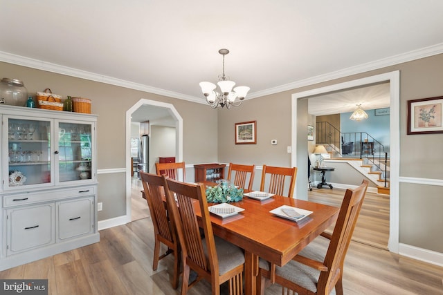 8807 Falkstone Ln, Alexandria, VA 22309 - dining space with a chandelier, light wood finished floors, arched walkways, crown molding, and baseboards