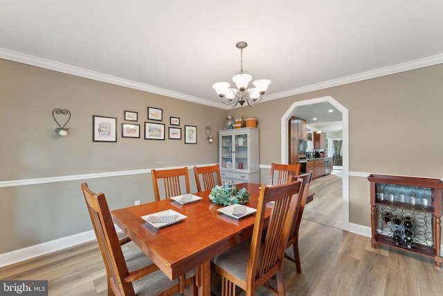 8807 Falkstone Ln, Alexandria, VA 22309 - dining room with an inviting chandelier, ornamental molding, arched walkways, and light wood-type flooring