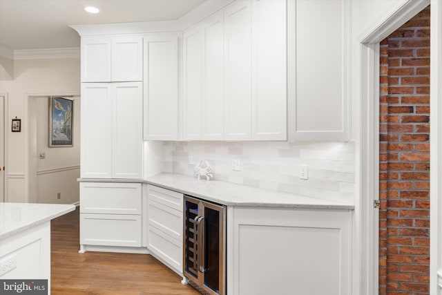 bar featuring ornamental molding, wine cooler, light wood-type flooring, recessed lighting, and a dry bar
