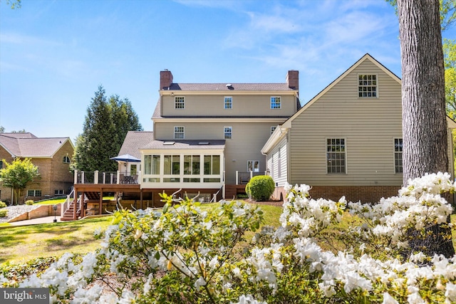 rear view of house with stairway, a deck, a chimney, and a sunroom
