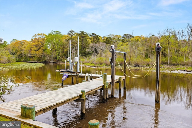 view of dock with a water view, a wooded view, and boat lift