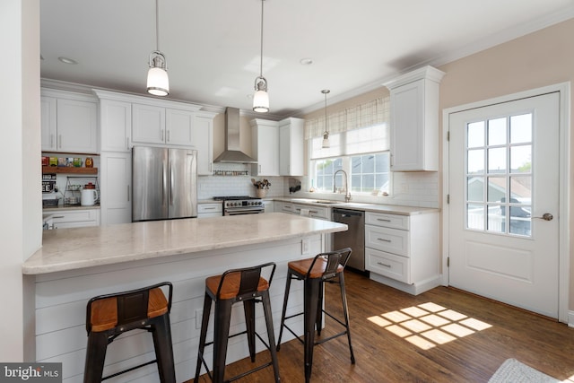 kitchen with appliances with stainless steel finishes, backsplash, a kitchen bar, and wall chimney exhaust hood