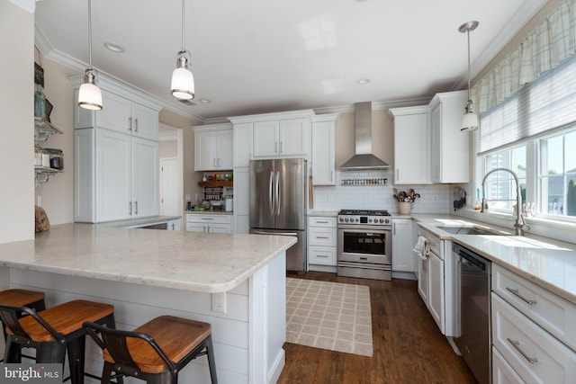 kitchen with wall chimney range hood, white cabinets, appliances with stainless steel finishes, and decorative backsplash
