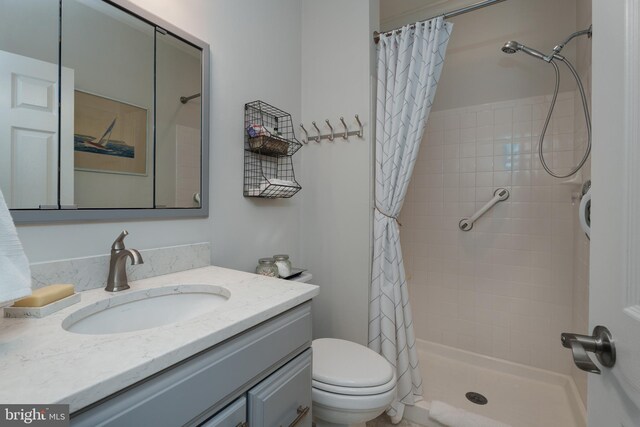 full bathroom with vanity, a tile shower, and toilet
