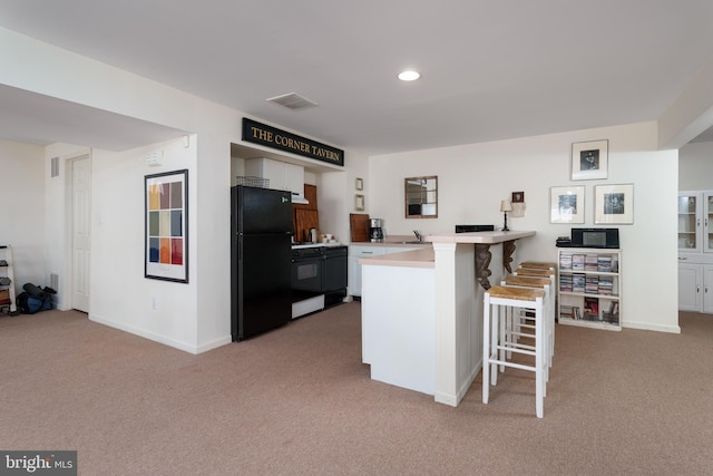 kitchen featuring a breakfast bar, carpet, freestanding refrigerator, a peninsula, and range with gas cooktop