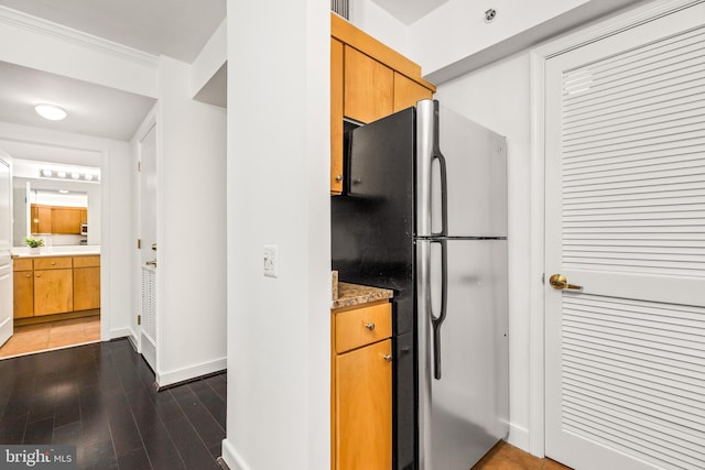 kitchen featuring baseboards, freestanding refrigerator, wood finished floors, and light countertops