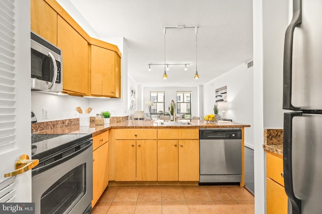 kitchen featuring visible vents, a peninsula, a sink, appliances with stainless steel finishes, and light tile patterned floors