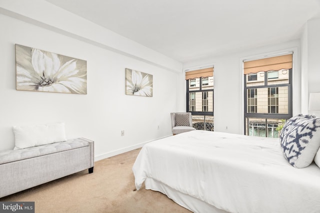 bedroom with baseboards and light colored carpet