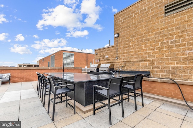 view of patio / terrace with outdoor wet bar, grilling area, exterior kitchen, and fence