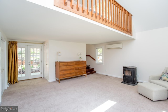 living area featuring stairs, a wall unit AC, a wood stove, and carpet floors