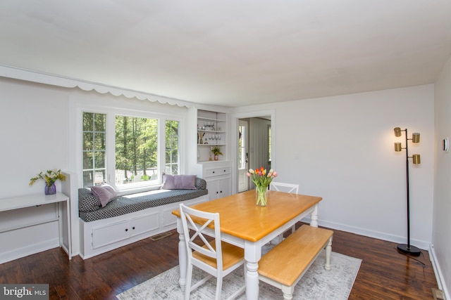 dining space featuring baseboards, visible vents, built in shelves, and dark wood-type flooring