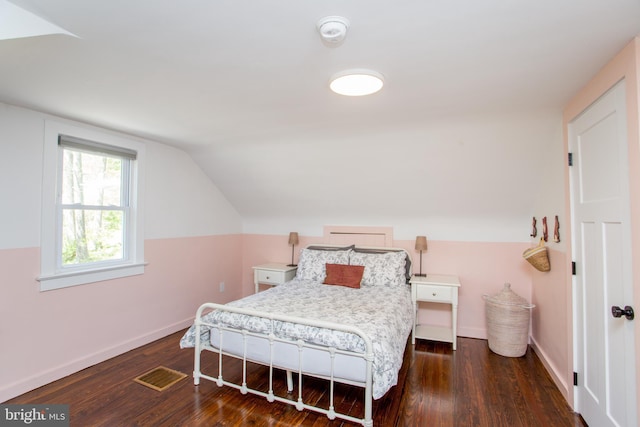 bedroom featuring dark wood-type flooring, baseboards, vaulted ceiling, and visible vents