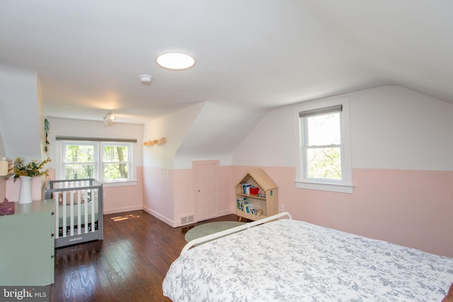 bedroom with visible vents, baseboards, vaulted ceiling, and hardwood / wood-style flooring