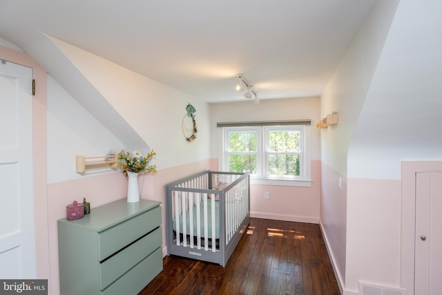 hallway featuring visible vents, baseboards, rail lighting, dark wood finished floors, and an upstairs landing