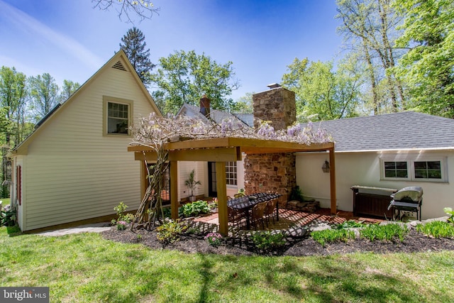 back of property with a yard, a chimney, a shingled roof, and a patio area