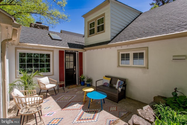 back of house featuring a patio, a shingled roof, stucco siding, and an outdoor living space