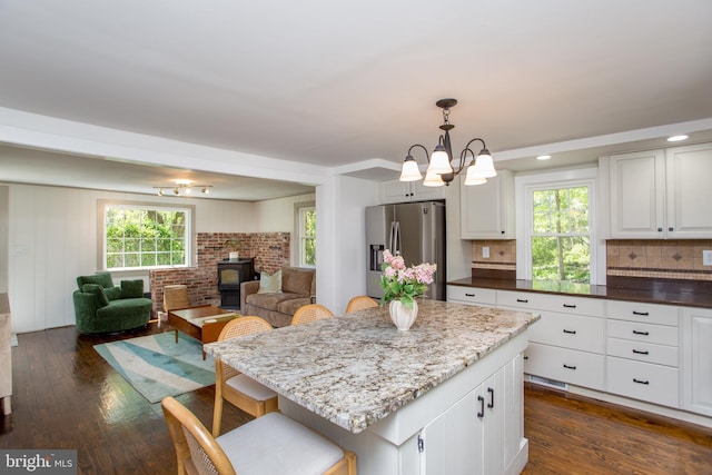 kitchen featuring decorative backsplash, dark wood-style flooring, open floor plan, stainless steel fridge, and white cabinets