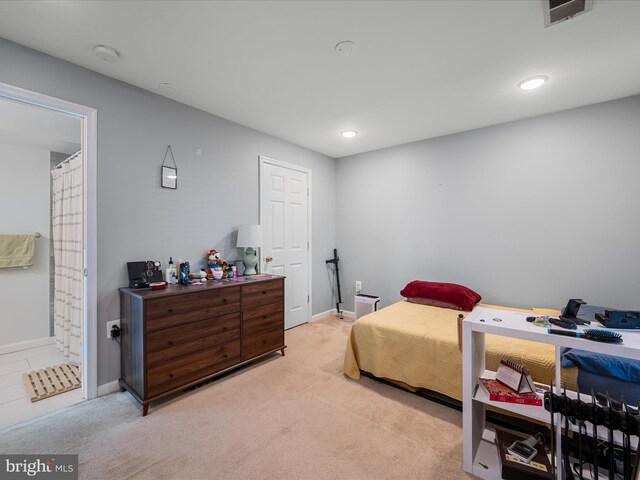 bedroom with visible vents, ensuite bathroom, baseboards, and light carpet