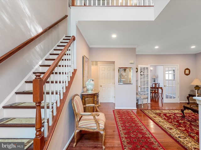 entrance foyer featuring crown molding, french doors, baseboards, wood finished floors, and stairs