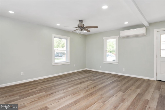 unfurnished room featuring a wall mounted AC, healthy amount of natural light, light wood-style floors, baseboards, and recessed lighting