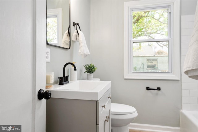 full bath featuring a tub, healthy amount of natural light, toilet, and vanity