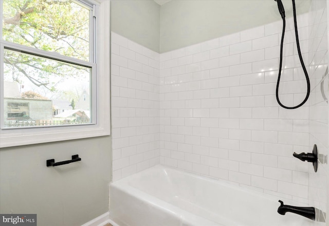 bathroom featuring healthy amount of natural light, tub / shower combination, and baseboards