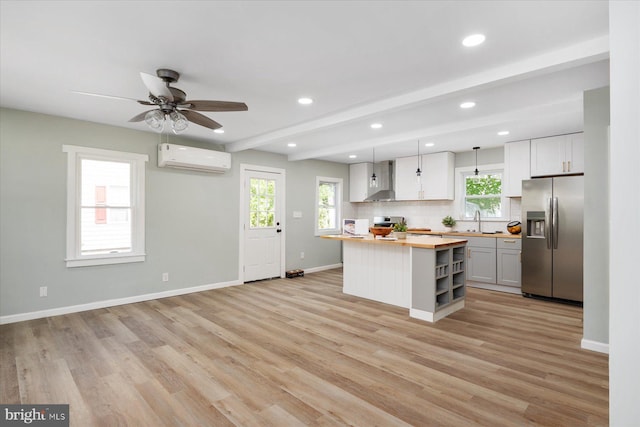 kitchen with stainless steel fridge, butcher block countertops, a wall mounted air conditioner, a sink, and backsplash