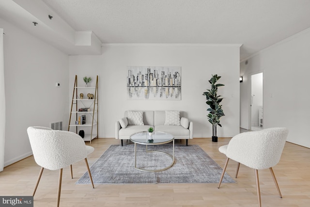 living area featuring crown molding, wood finished floors, and visible vents
