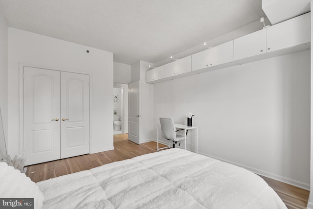 bedroom with baseboards, a textured ceiling, and wood finished floors