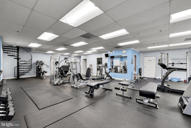 exercise room featuring baseboards and a paneled ceiling