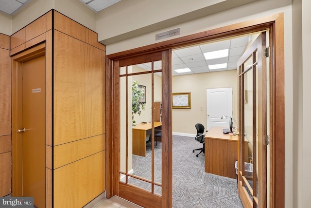 office space featuring baseboards, light colored carpet, and a drop ceiling