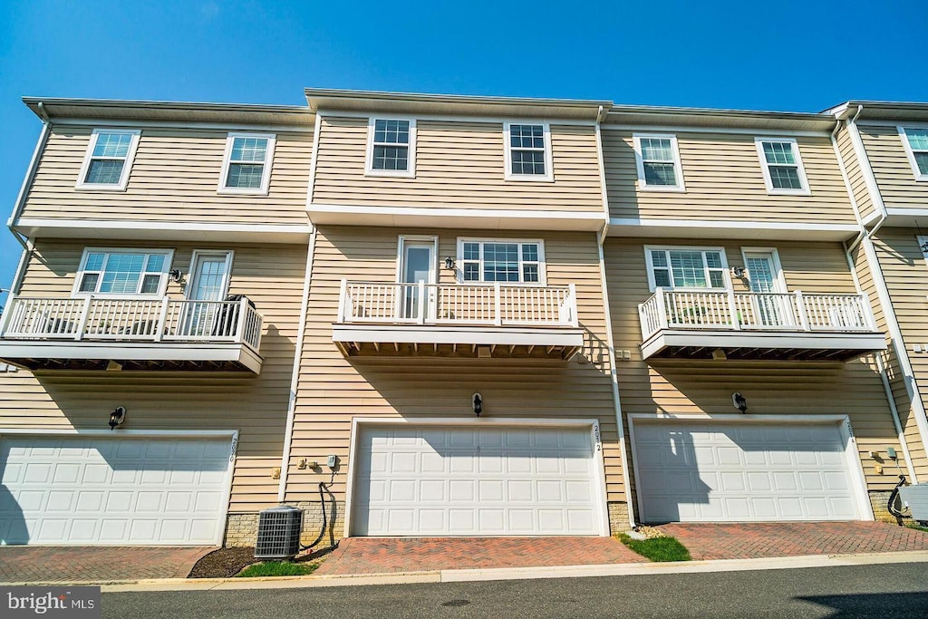 view of front of home with central air condition unit, an attached garage, and driveway