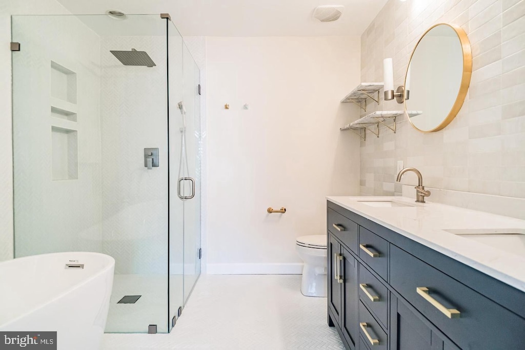 full bath with double vanity, a freestanding tub, tasteful backsplash, a sink, and a stall shower