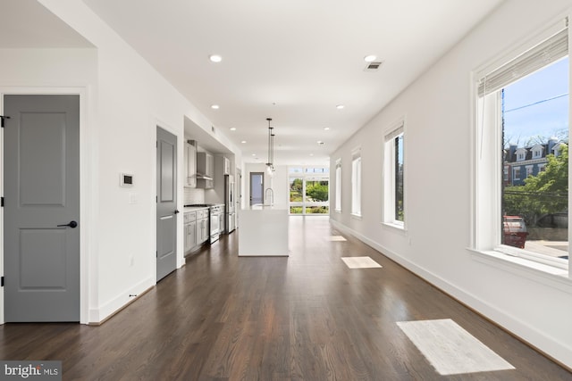 hall featuring a healthy amount of sunlight, recessed lighting, dark wood finished floors, and visible vents