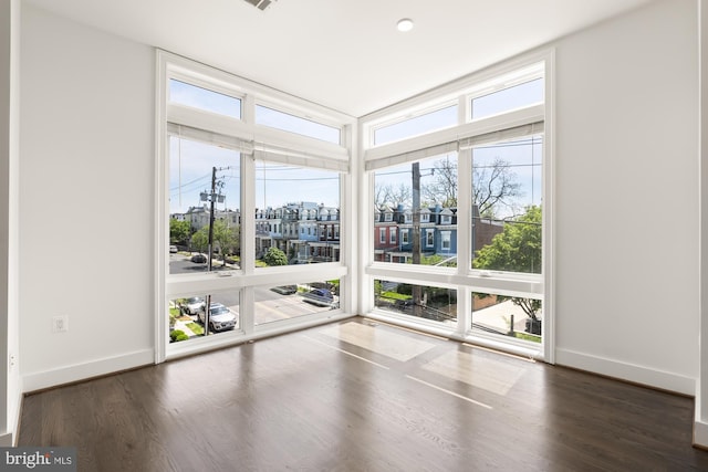 unfurnished room featuring baseboards and dark wood-style floors
