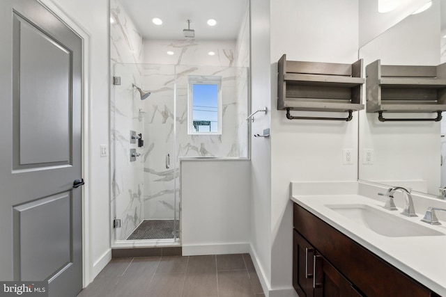 full bath featuring baseboards, vanity, and a marble finish shower