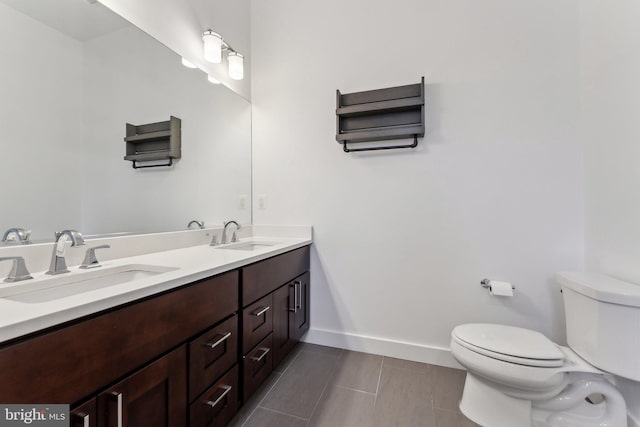 bathroom featuring baseboards, toilet, tile patterned floors, and a sink
