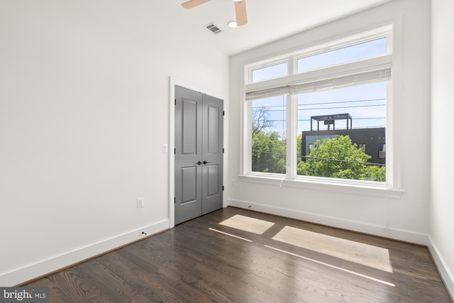 spare room featuring baseboards, a ceiling fan, dark wood-type flooring, and visible vents