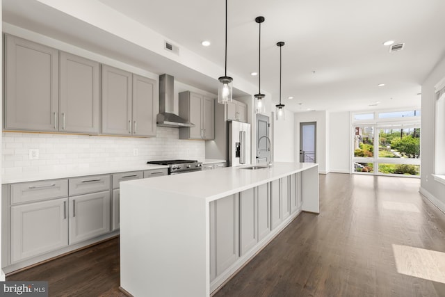 kitchen with backsplash, gray cabinetry, a sink, high end refrigerator, and wall chimney exhaust hood