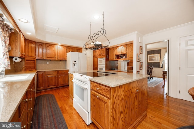 kitchen with light wood finished floors, white appliances, a kitchen island, and crown molding