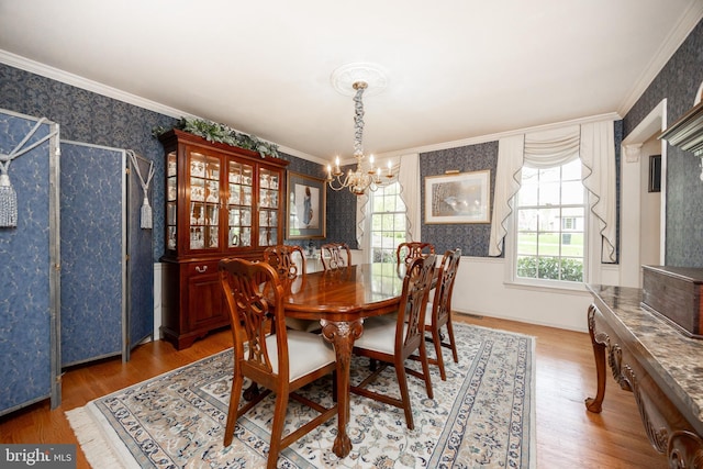 dining room with wallpapered walls, wood finished floors, a chandelier, and crown molding