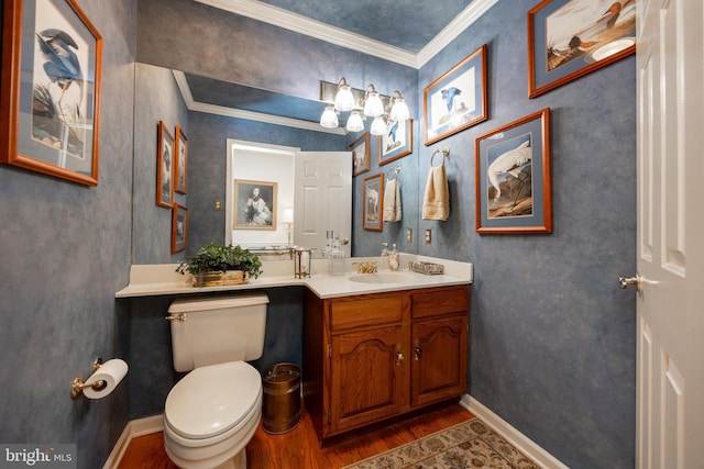 bathroom with toilet, baseboards, wood finished floors, crown molding, and vanity